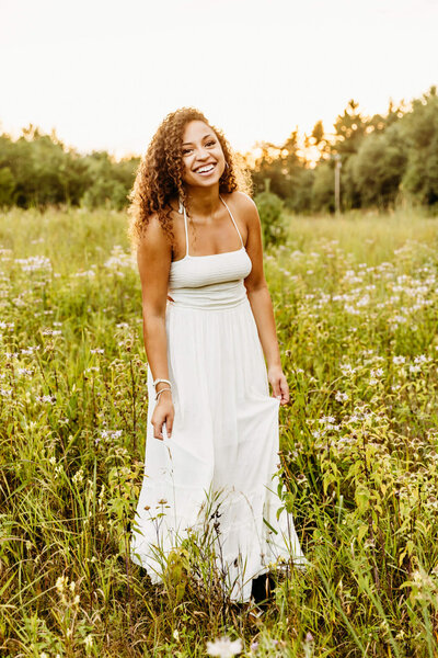 senior girl laughing while playing in a field of wildflowers