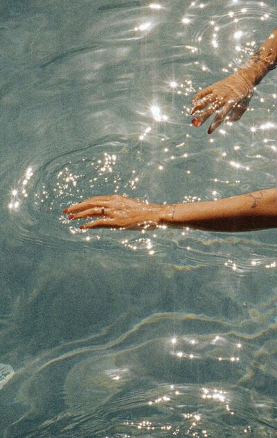 Woman’s hands gliding through blue water – somatic imagery for emotional flow and healing
