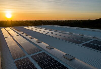 Large-scale solar panel installation on a commercial rooftop during sunset, highlighting clean energy solutions for businesses