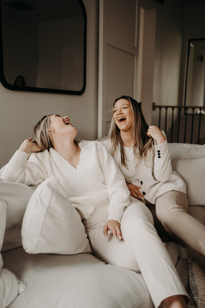 two girls sitting on a couch laughing and hanging out on a couch