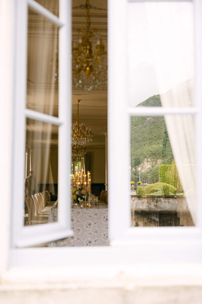 Photo taken from outside that is looking in through the window to the wedding tablescape set up inside