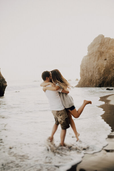Couple hugging on a beach and stood slightly in the water