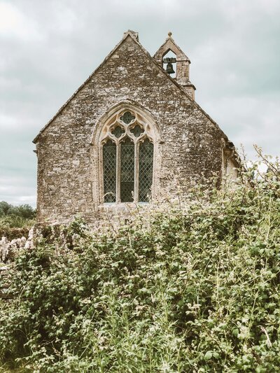 A very old, traditional church building with greenery in the foreground