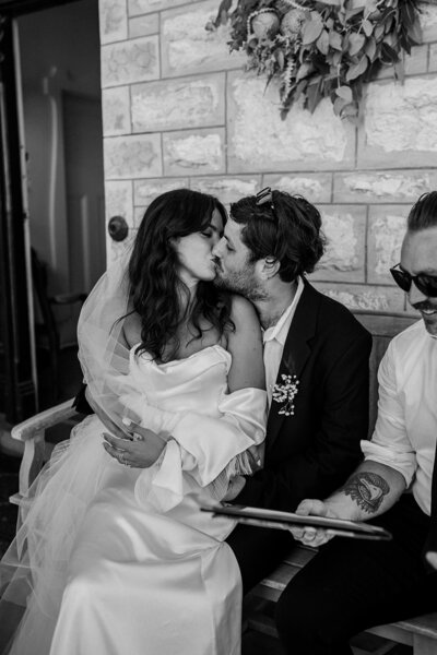 couple sharing a kiss while signing documents after their melbourne wedding ceremony