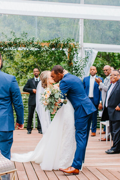 groom dips bride for a kiss in the aisle after their ceremony