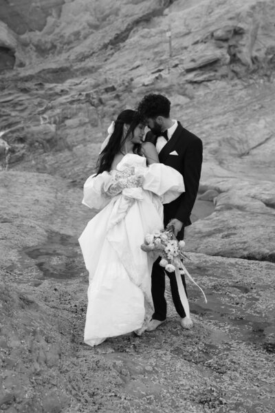 Black and white photo of bride and groom embracing with mountainous background