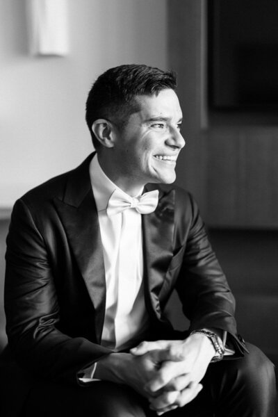Black and white portrait of groom smiling in tuxedo before ceremony, captured by wedding photographer in Toronto