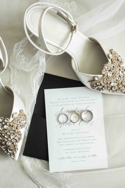 Flatlay with wedding shoes, rings, and stationery