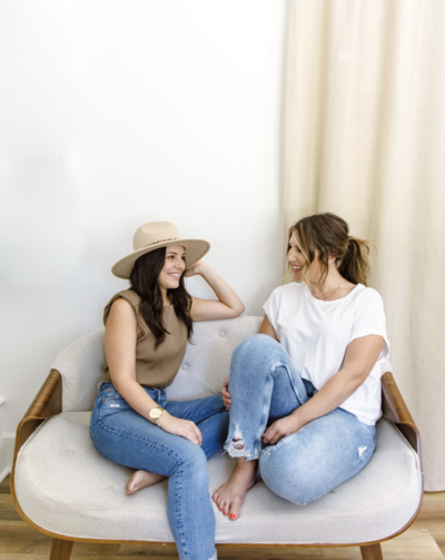 women sitting on white chair and smiling
