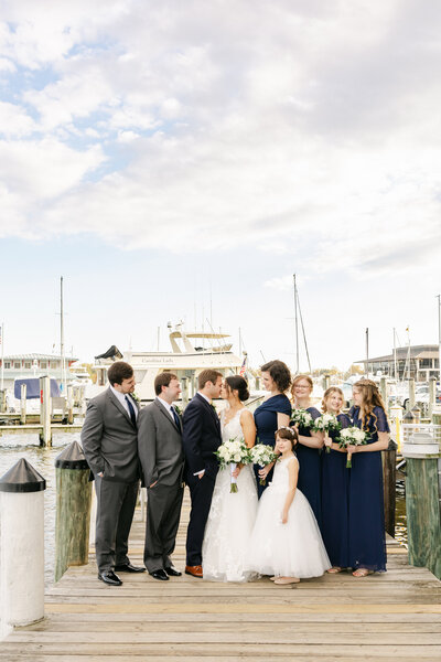 black and white photo of bride and groom in front of boat shed