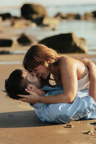 couple running on beach with mountain views at sunset