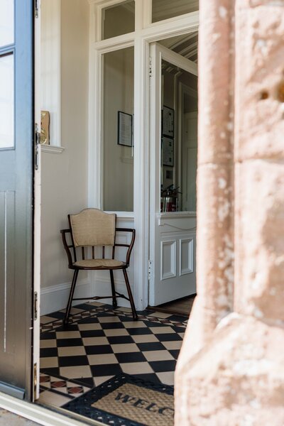 The front entrance of Kinclune House Wedding Venue is filled with light and a chair is photographed.
