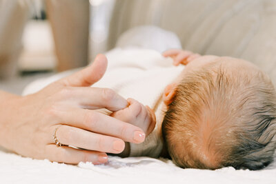 A baby wrapping his hand around his mom's finger