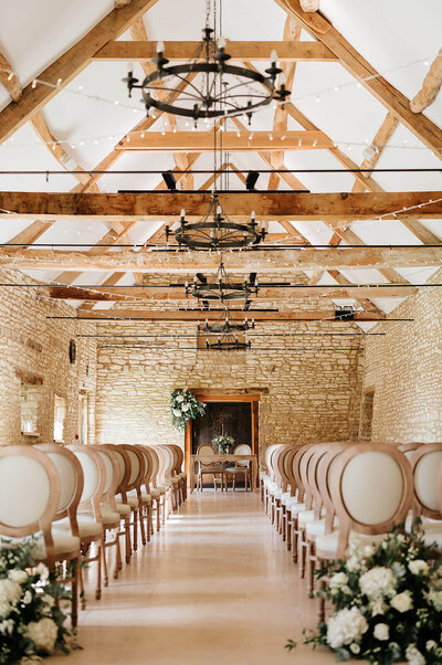 Light and airy wedding ceremony setup in Caswell House barn with fairy lights and elegant styling
