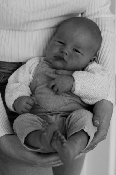 Zwart-witfoto van een baby die in de armen van een vrouw ligt, met een liefdevolle en beschermende uitstraling.