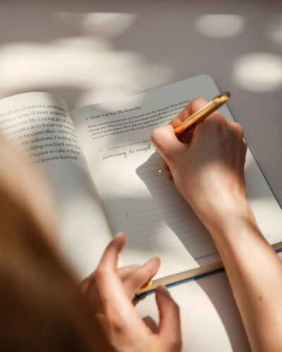 Person writing in journal, reflecting self-inquiry and coaching for self-trust