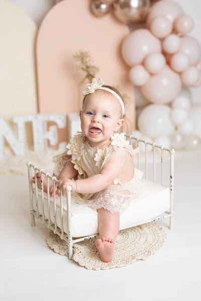 Baby girl wearing a green romper with matching bow headband for her sitter session in Minnesota.