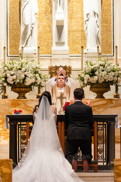 a bride and groom participating in a catholic wedding ceremony