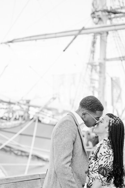 South Street Seaport, NYC.  Couple stands close about to kiss, scenic view in front of boats.  Proposal Photographer Corey Lamar Photography; NYC