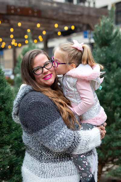 Daughter kissing mother on cheek in holiday portrait