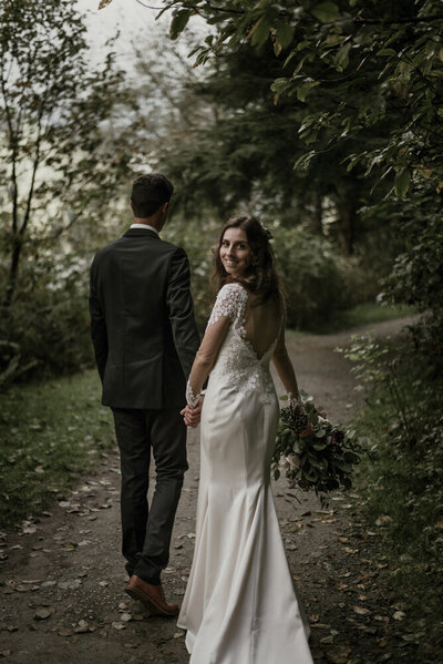 wedding couple walking in the forest holding hands