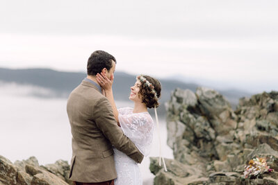 Bride and groom standing hand in hand with a mountain lake behind them during their intimate Virginia elopement, photographed in natural light and soft tones.

