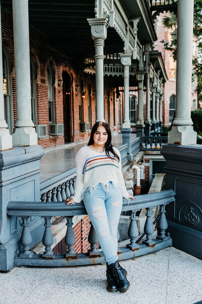beautiful senior girl standing in front of a beautiful and old arcitectual building