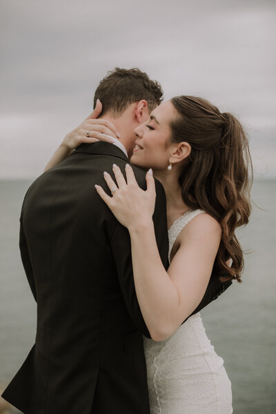 wedding couple hugging by the water