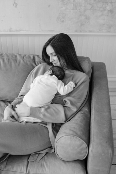 Mother relaxes on couch with baby during newborn session. North Shore Portrait Photographer Deborah Zoe.