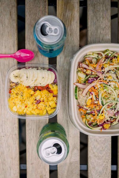 Healthy, nutritous meals in tupperware next to two cans of sparkling water.