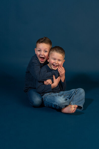 two boys in jeans hugging each other