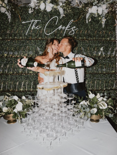 A bride and groom are shown cutting their wedding cake, both smiling broadly.