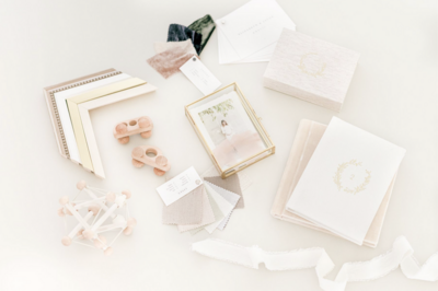 Flat lay image of heirloom photo artwork featuring a printed portrait in a gold frame, neutral fabric swatches, and wooden baby toys.