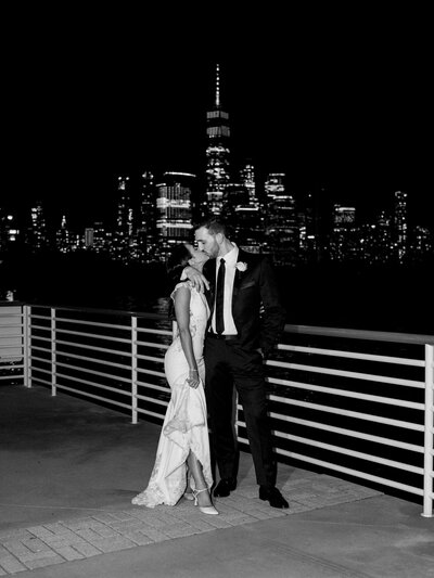 Bride and groom taking nighttime portraits overlooking Manhattan with the skyline in the background.