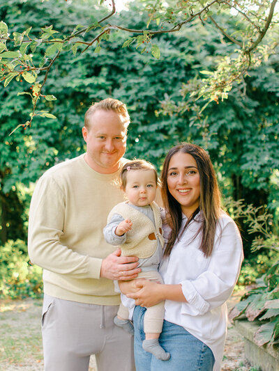 Parents and their one year old daughter cuddle in a park in Amsterdam, during a photoshoot.