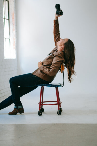 denver commercial photographers photographs brand images of business owner sitting in a blue arm chair in a studio session