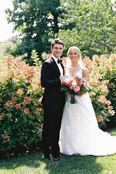 Bride and groom smiling in garden at Gervasi Vineyard wedding.


