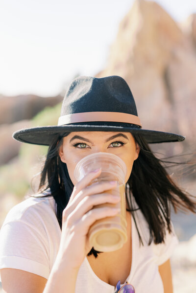 girl drinking coffee with green eyes and black hat