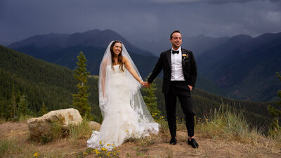 Bride and groom pose on mountain top in aspen