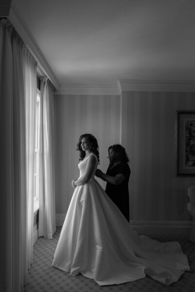 A person helping someone put on a wedding dress 