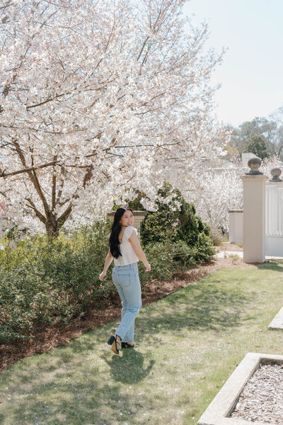 Woman walking under blooming spring trees during a bright lifestyle photo session in Alabama — EC Photography