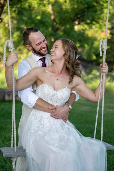 a bridge on a swing with the groom standing behind her hugging her