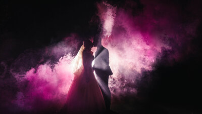 A wedding couple kissing with smoke bombs at night