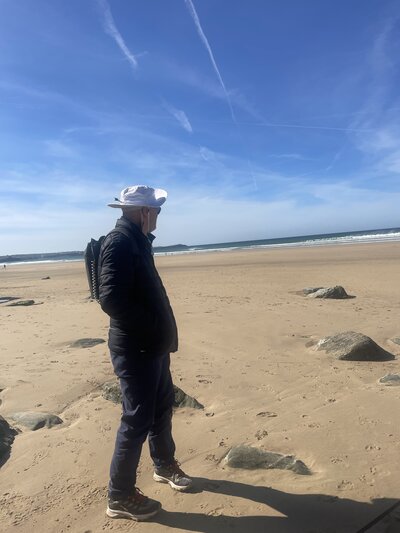 NIgel aat the beach while wearing the Optune device