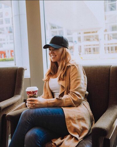 Woman wearing a baseball hat holding a cup of coffee