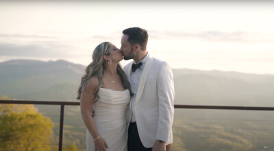 Bride and groom kiss with mountains in background