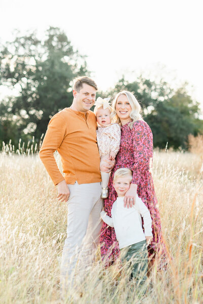a family with a boy and a girl poses in a field of grass for their family pictures in Austin, TX. 