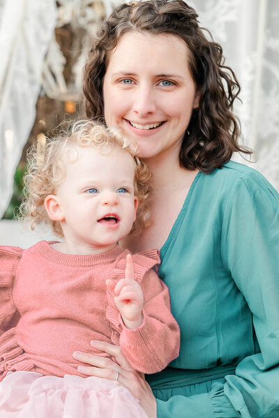 Justine, the photographer at Justine Renee Photography, holds her young daughter and smiles for the camera.