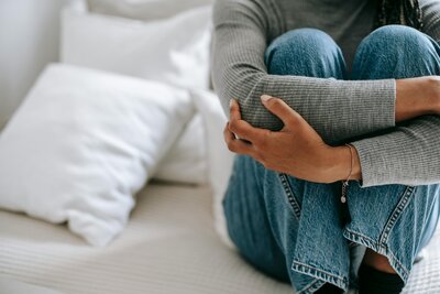 A woman hugging her knees to her chest, looking pensive—symbolizing anxiety, depression, and the need for compassionate mental health support