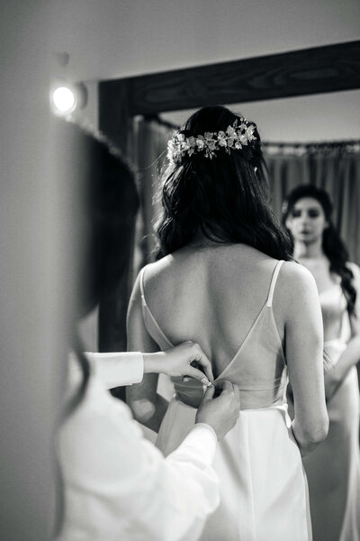 Most Valuable Bridesmaid Bridal assistant helping bride into wedding dress on morning of wedding